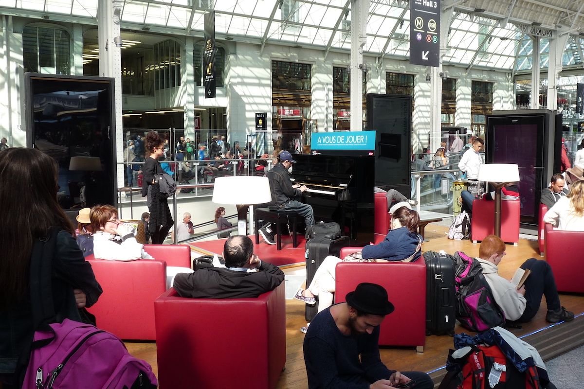 Joueur de piano à Paris Gare de Lyon, au milieu de passagers en salle d'attente